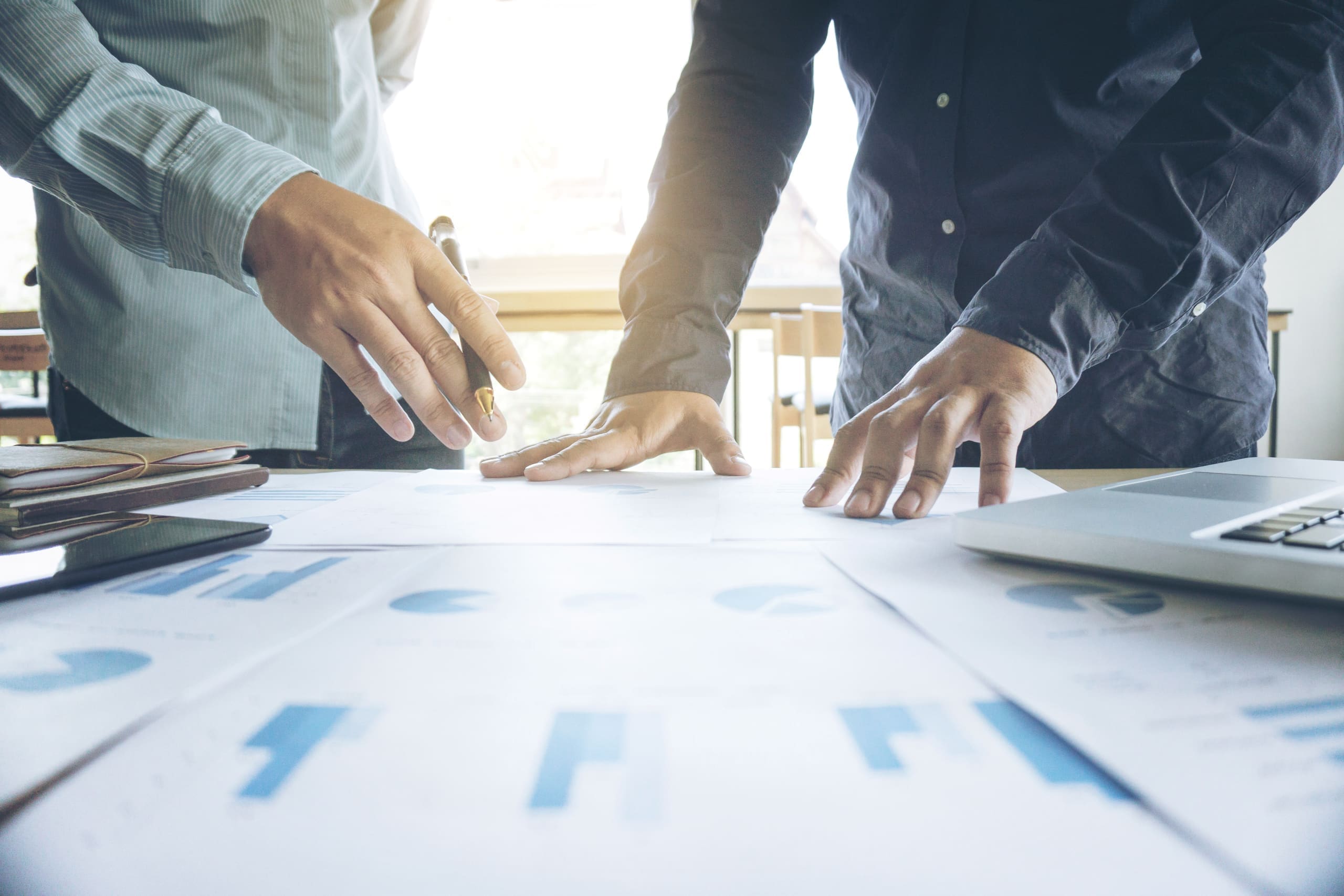 Two analysts reviewing market charts and floor plan data at a work table